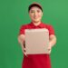 happy_young_delivery_woman_red_uniform_cap_showing_cardboard_box_looking_front_smiling_cheerfully_standing_green_wall_141793_71598